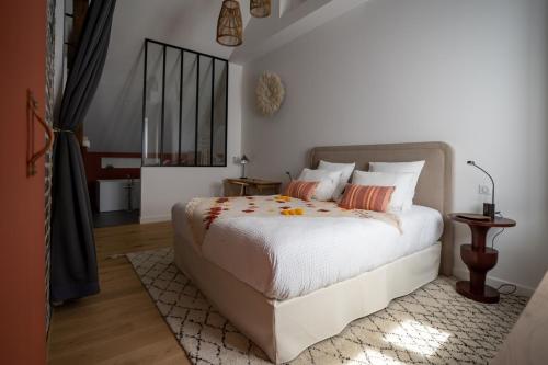 een slaapkamer met een bed met witte lakens en oranje kussens bij KRAFFT, centre ville, climatisé, baignoire double - La Clé des Sacres in Reims