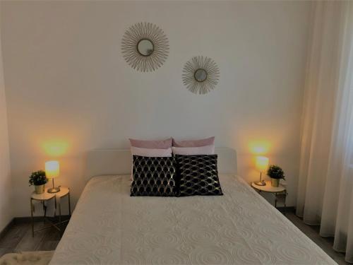 a bedroom with a bed with two lamps and two mirrors at Glamour Apartman in Tapolca