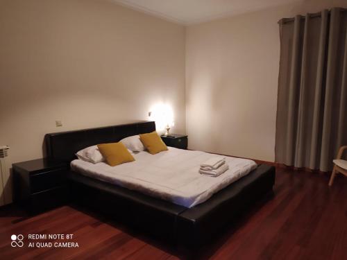 a bedroom with a large bed with yellow pillows at Quinta do Carvalho - Nature Guest Houses in Guimarães