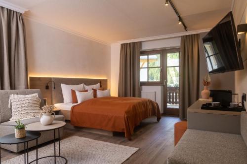 ein Hotelzimmer mit einem Bett und einem Sofa in der Unterkunft Verwöhn-Harmoniehotel Mandarfnerhof in Sankt Leonhard im Pitztal