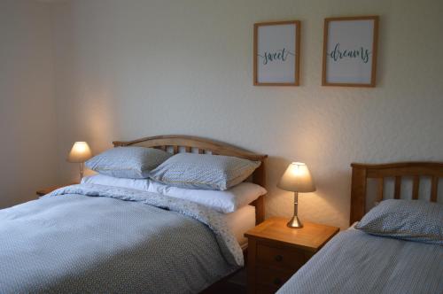 a bedroom with two beds and two lamps and pictures on the wall at Kilronan Self Catering - Eoropie, Isle of Lewis in Eoropie