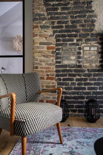 a chair in a room with a brick wall at KRAFFT, centre ville, climatisé, baignoire double - La Clé des Sacres in Reims