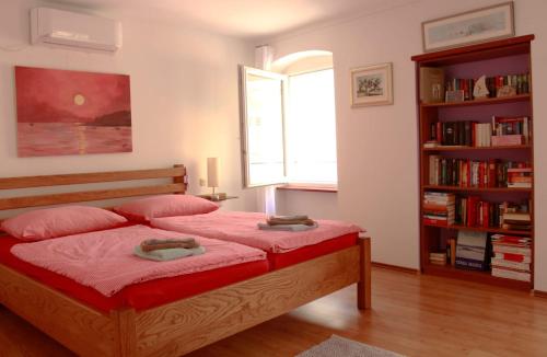 a bedroom with a bed with red sheets and a book shelf at Apartment Roby in Vrsar