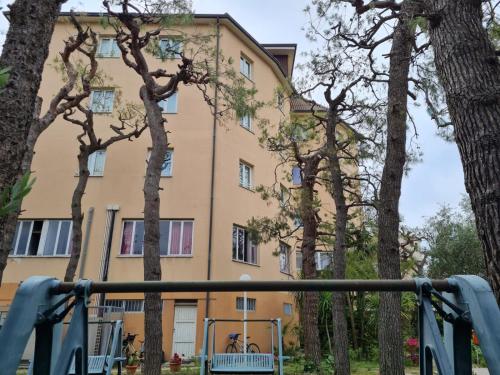 a building with trees in front of a playground at Hotel La Terrazza in Porto San Giorgio