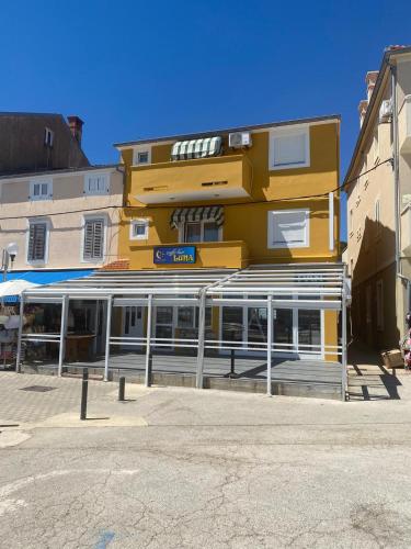 a tall yellow building with a store front at Central Apartments Preko in Preko