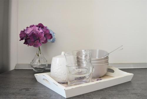 a tray with a vase and glasses and a vase with flowers at Central Apartments Preko in Preko