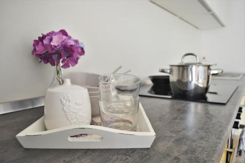 a tray with glasses and a vase with flowers on a counter at Central Apartments Preko in Preko