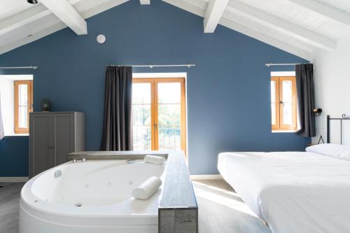 a blue room with a bath tub next to a bed at Jardines Villaverde in Villaverde de Pontones
