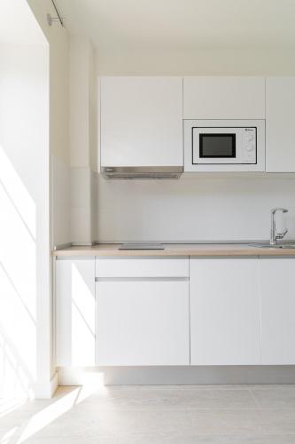 a kitchen with white cabinets and a microwave at Jardines Villaverde in Villaverde de Pontones