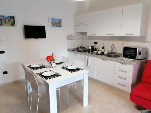 a white kitchen with a white table and a red couch at Suite Maria in Agliana