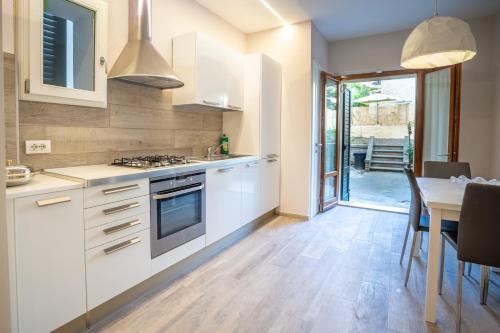 a kitchen with white cabinets and a table and a dining room at EM Apartment in Siena