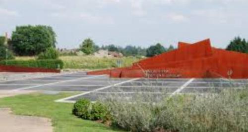 an empty parking lot with an orange fence at La roulotte des Trois Arbres in Oradour-sur-Glane