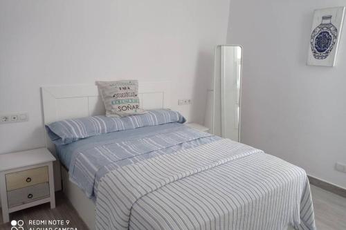 テギセにあるPrecioso apartamento con terraza en Teguiseの白いベッドルーム(ストライプ毛布付きのベッド付)
