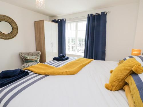 una camera da letto con un grande letto bianco con tende blu di Sail Away, 17 Union Mill a Whitby