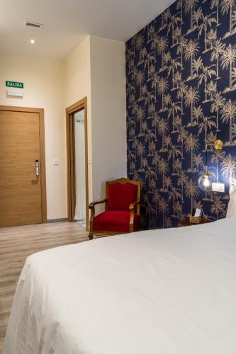 a bedroom with a bed and a red chair at Four Rooms Hostel in Lugo