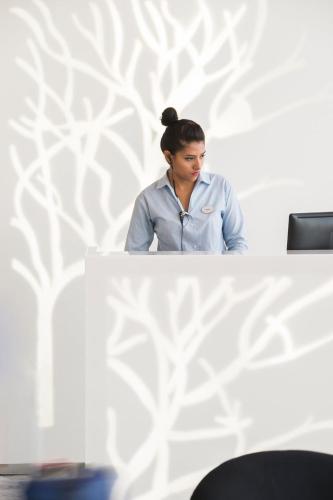 a woman standing behind a table in an office at Fiesta Inn Merida in Mérida