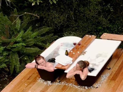 two people in a hot tub with a table at Wonderland Makarora Lodge in Makarora