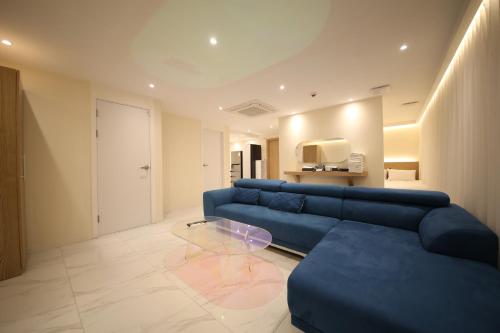 a living room with a blue couch and a glass table at Hotel Vantt in Gwangju