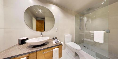 a bathroom with a sink and a toilet and a mirror at Distinction Dunedin Hotel in Dunedin