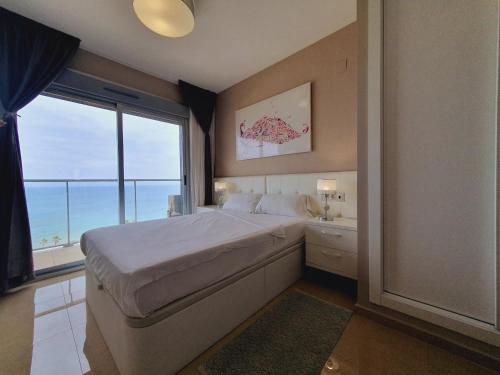 - une chambre avec un grand lit et une grande fenêtre dans l'établissement Holiday Deluxe Apartment Miramar Marina d'or, à Oropesa del Mar