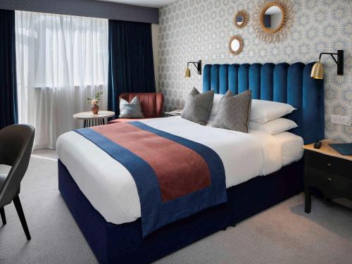 a bedroom with a large bed with a blue headboard at Mercure Bournemouth Queens Hotel and Spa in Bournemouth