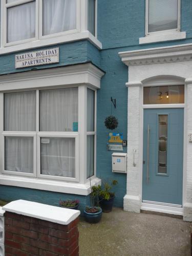 a blue house with a blue door and a sign on it at Marina Holiday Apartments in Bridlington