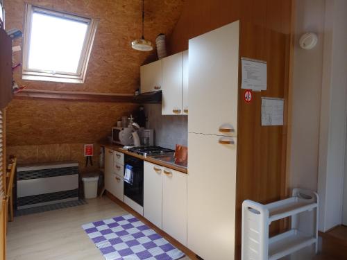 uma pequena cozinha com armários brancos e uma janela em Apartment De Paprente em Merkem