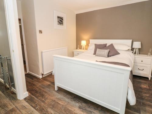 a large white bed in a room with wooden floors at The Gables in Castleton