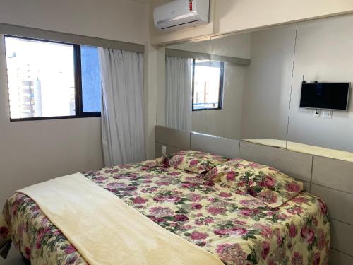 a bedroom with a bed with a floral bedspread at Apto Top Custo-Benefício Qualidade e preço que surpreendem in Maceió