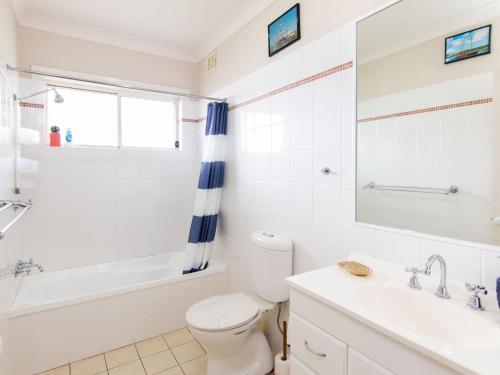a bathroom with a toilet and a tub and a sink at Tokelau Townhouse 1 in Tuncurry