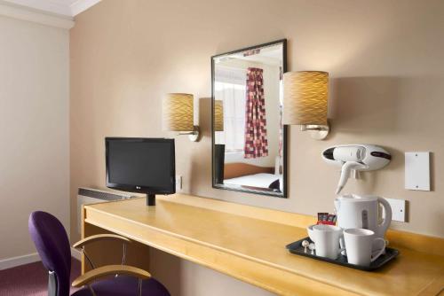 a room with a desk with a tv and a mirror at Days Inn Hamilton in Hamilton