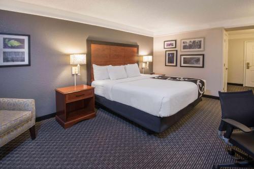 a hotel room with a large bed and a chair at La Quinta Inn & Suites by Wyndham San Antonio Riverwalk in San Antonio