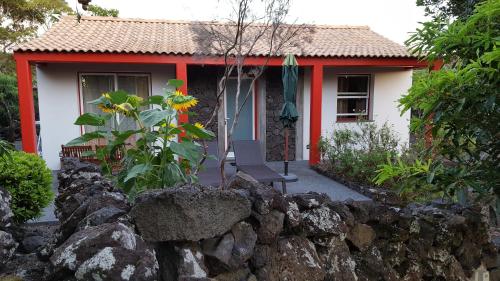 a small red and white house with a rock fence at Casa da estrela canopus in Cabeço Chão