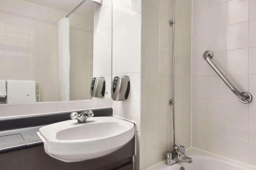 uma casa de banho branca com um lavatório e um chuveiro em Days Inn by Wyndham Sevenoaks Clacket Lane em Westerham