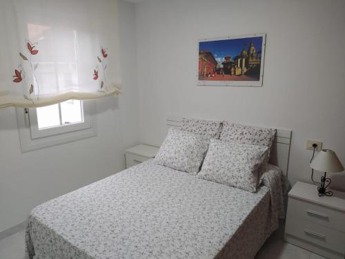a white bedroom with a bed and a window at Apartamento en primera línea de playa in Laxe