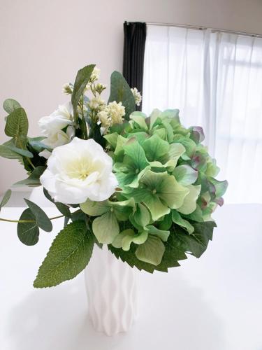 a white vase filled with white flowers in a window at OUCHI HOTEL Kanayama-cho with Dogs in Hiroshima