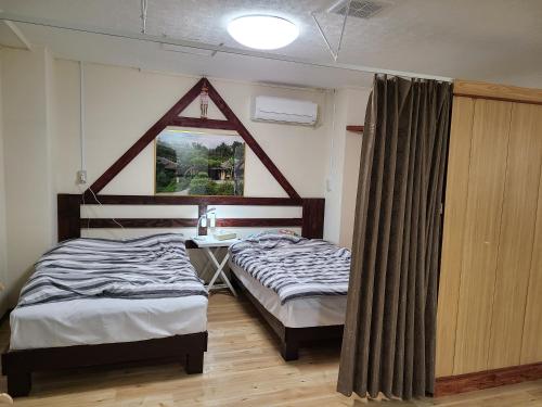 een slaapkamer met 2 bedden, een bureau en een raam bij Aoi sanmyaku in Awase