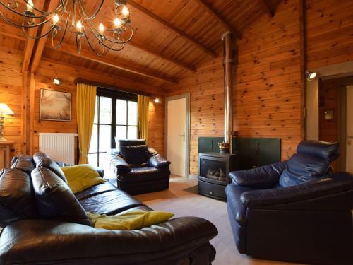 a living room with leather furniture and a fireplace at Cosy chalet in Durbuy in a beautiful hiking area in Durbuy