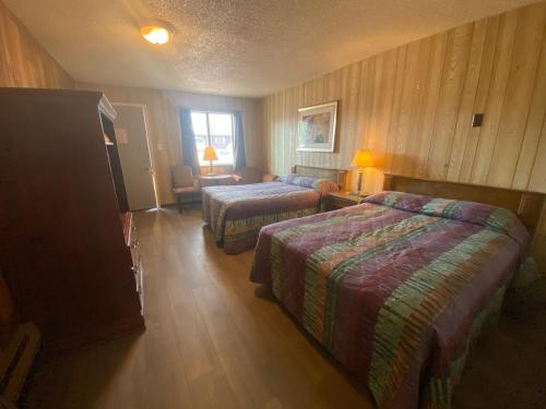 a hotel room with two beds and a chair and a window at Round-Up Motel in Cheyenne