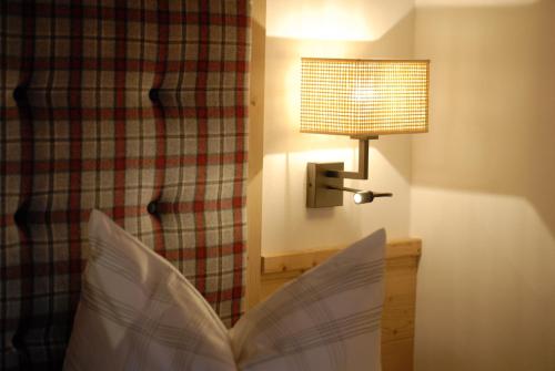 a bed with a book and a lamp in a room at Mühlerhof in Funes