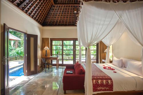 a bedroom with a canopy bed and a living room at Komaneka at Monkey Forest Ubud in Ubud