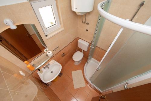 bagno con lavandino, servizi igienici e specchio di Apartments Ruzica - sea view a Igrane
