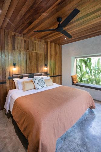 a bedroom with a large bed with a ceiling fan at Surfing Temple Boutique Hotel in General Luna