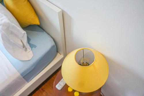 a yellow lamp on a table next to a bed at WECOZY HANOI - Railway Side, The Old Quarter in Hanoi