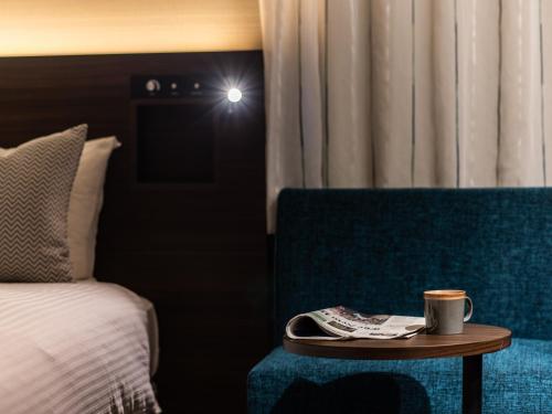 a hotel room with a bed and a table with a coffee cup at Hotel Vista Matsuyama in Matsuyama