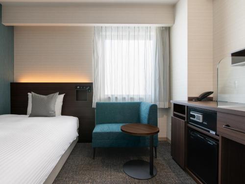 a hotel room with a bed and a blue chair at Hotel Vista Matsuyama in Matsuyama