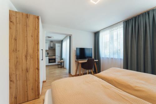 a bedroom with a bed and a desk with a television at Naturoase Appartements Mirnock in Afritz