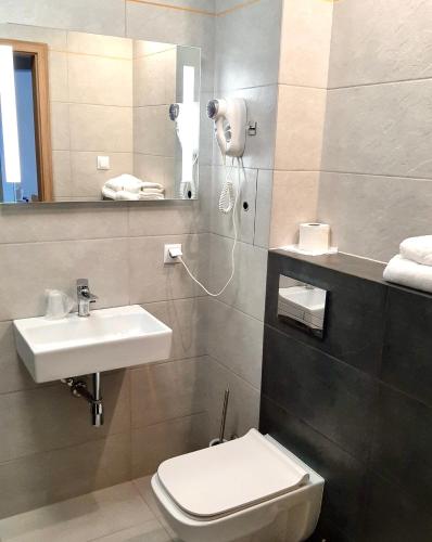 a bathroom with a sink and a toilet and a mirror at Poleczki Residence Apartments in Warsaw