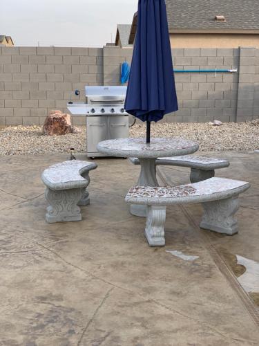 an umbrella sitting on a table with two benches at New Bullheadcity Pool Home Great Rates 5 Star in Bullhead City