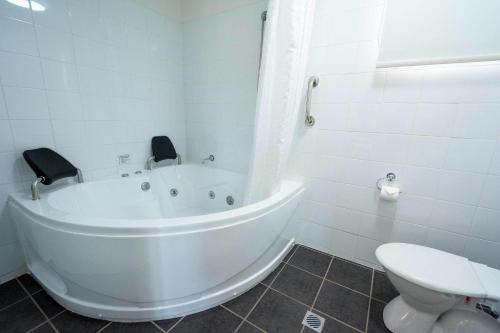 a white bathroom with a tub and a toilet at Darwin Resort in Darwin
